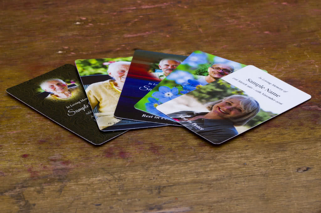 5 wallet memorial cards placed on a weathered wooden surface. 