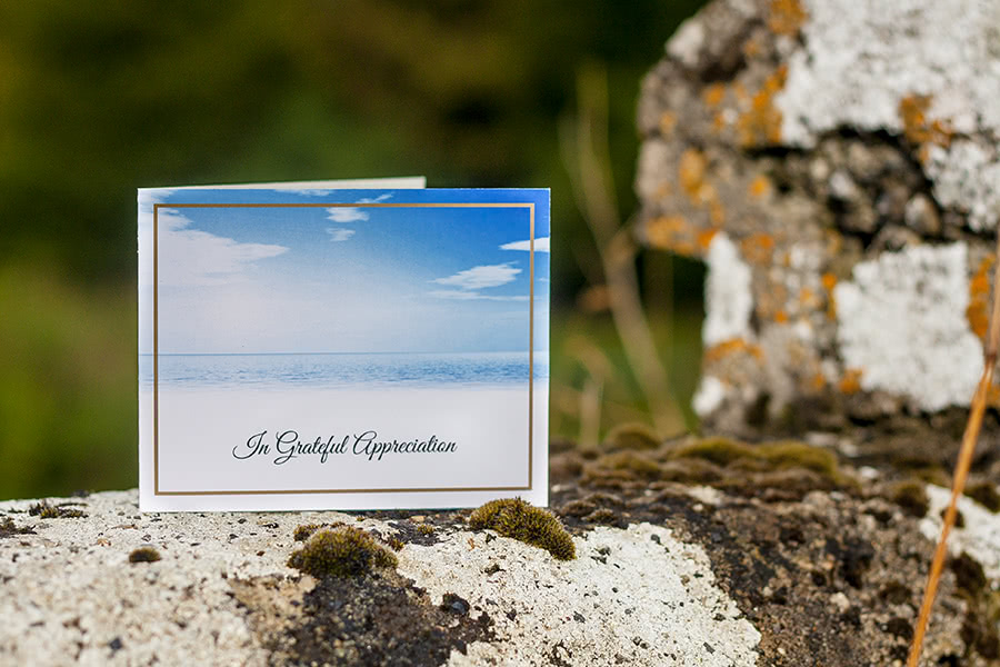 Acknowledgemen Card, front, sky themed design. The card is placed on an old overgrown stone wall.
