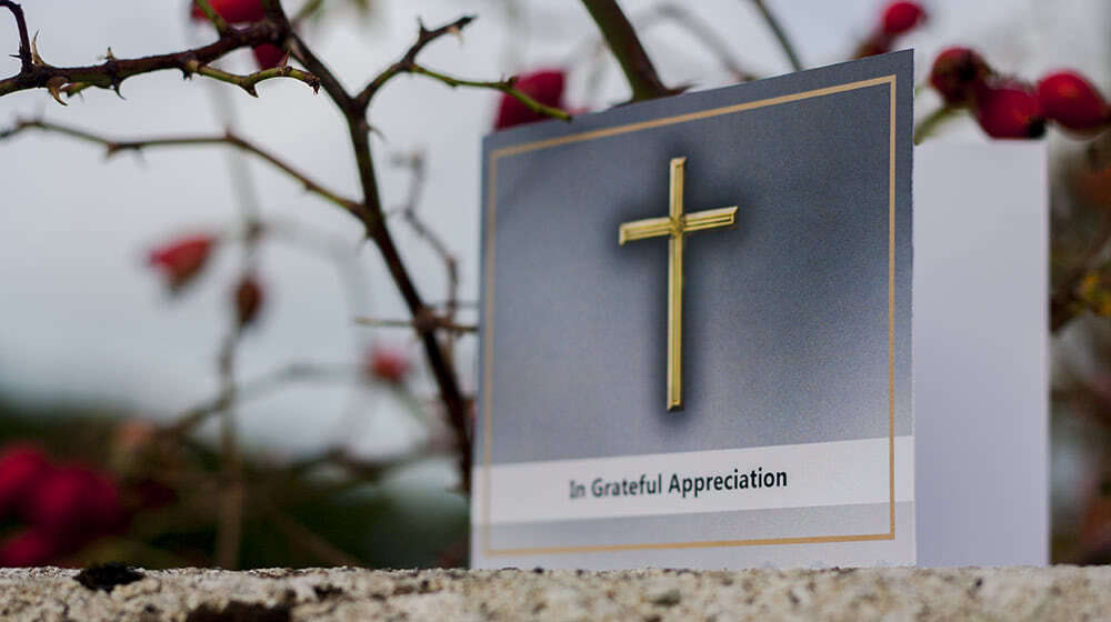 Thank you card with large golden cross and "In Grateful Appreciation" writing on the front. Shot outdoors, foggy weather, Ireland.