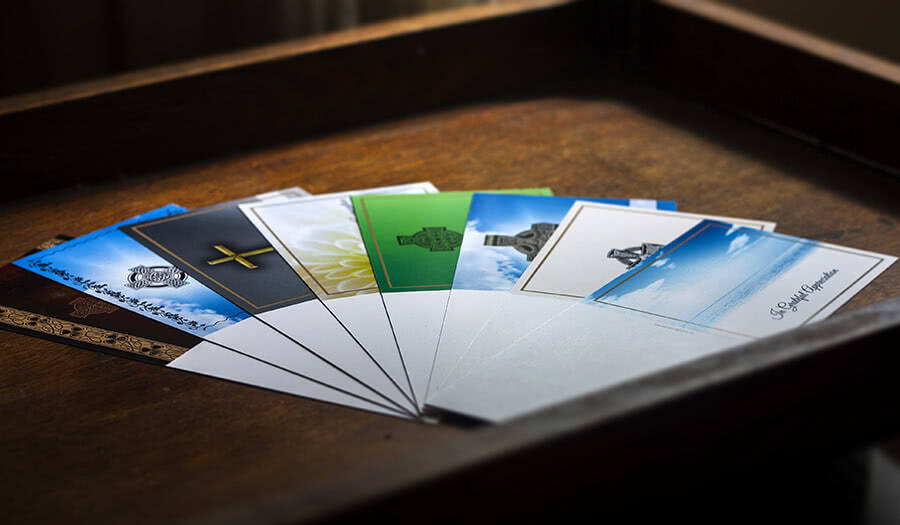 Multiple 4-page acknowledgement cards, flat, placed on a wooden surface, low light.